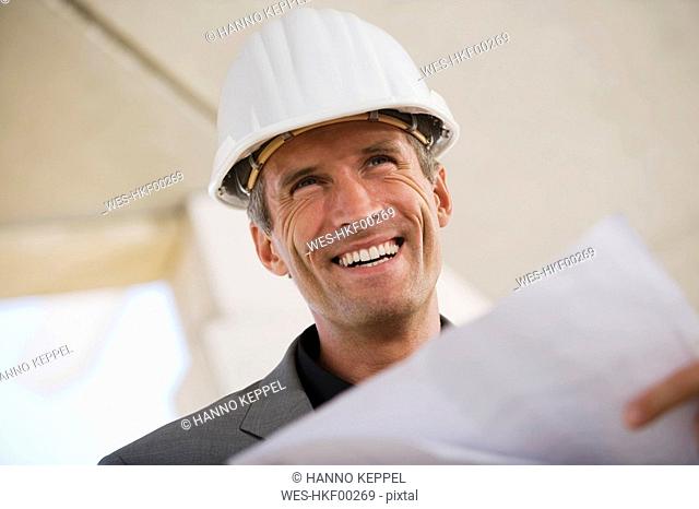 Man holding blueprint, smiling, portrait