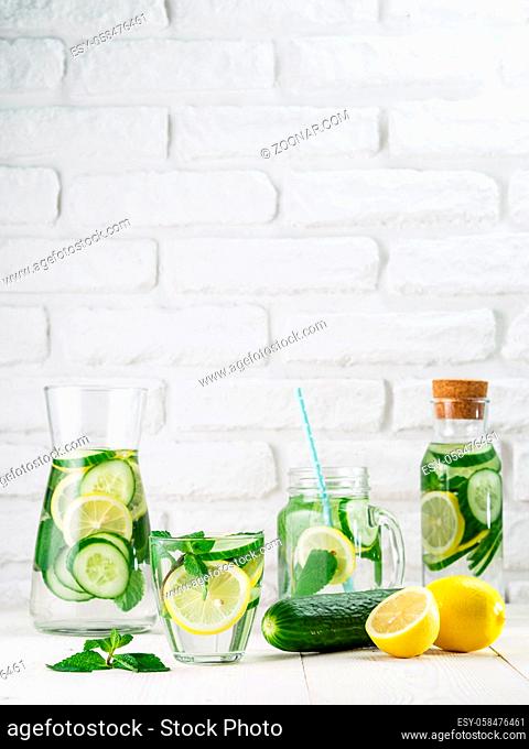 Infused detox water with cucumber, lemon and mint in different glass bottles on white table. Diet, healthy eating, weight loss concept. Copy space