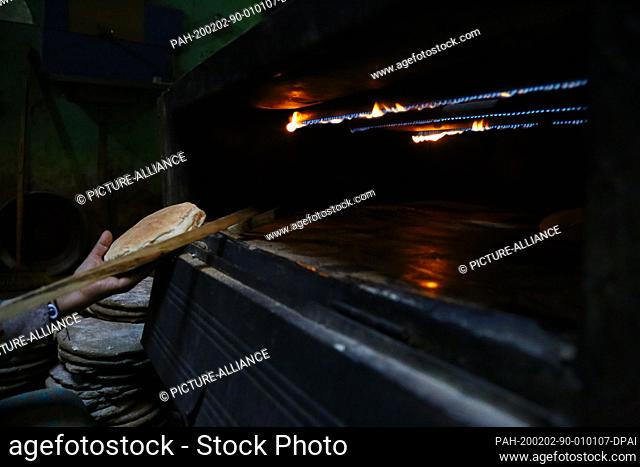 29 January 2020, Egypt, Manfalut: A picture provided on 02 February 2020 shows a woman removing from the oven a Sun Bread