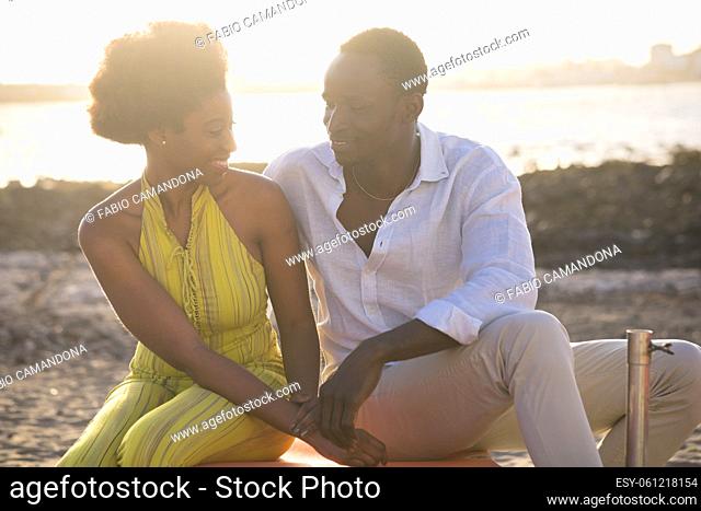Romantic young black couple man and woman smile and enjoy spending time leisure together with beach and sunset in background