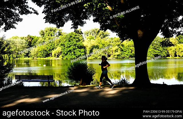 13 June 2023, Lower Saxony, Hanover: A woman jogs along the Maschsee lake in Hannover in the morning...Today there is a lot of sunshine and it remains mostly...