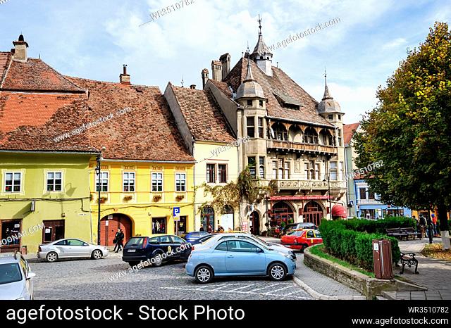 Sighisoara, Romania - October 19th, 2016: View of modern streets with people and cars in historic center of Sighisoara, Transylvania region, Romania
