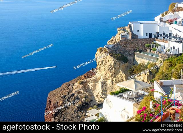 Greece. Sunny summer day in Santorini. Buildings and terraces with flowers on the caldera with seaview