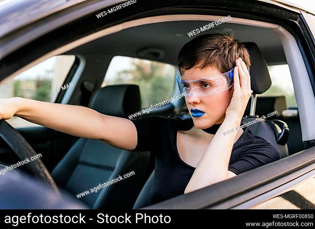 Woman with blue lipstick wearing smart glasses driving car