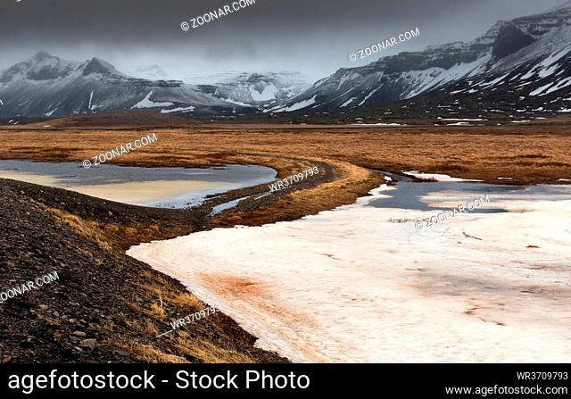 Typical Icelandic dramatic landscape with frozen lake and mountains covered in snow in Iceland