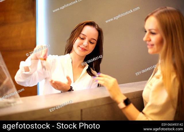 Young female receptionist working in beauty salon and talking with female customer