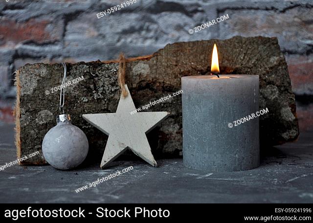 Brennende Kerze, Dekoration und Holzscheit vor Ziegelmauer - Burning candle, decoration and wood billet in front of brick wall