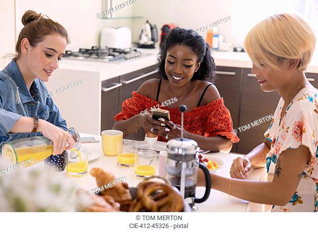 Young women friends enjoying breakfast at kitchen table