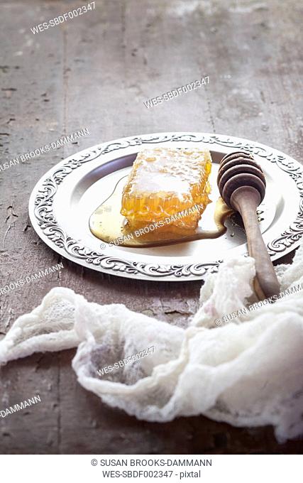 honeycomb with honey and honey spoon on tin plate