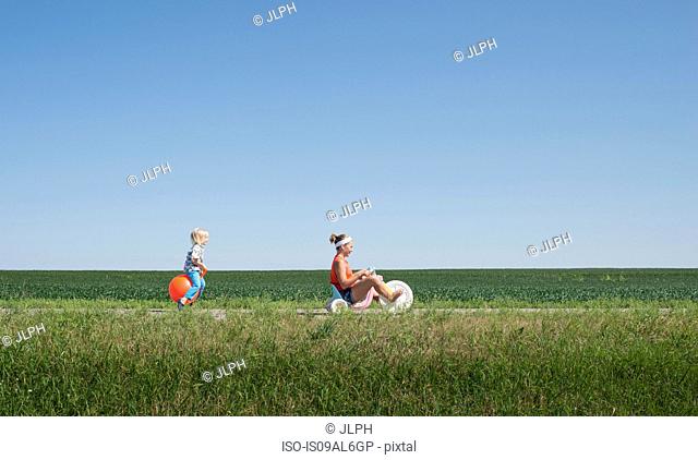 Teenage girl riding tricycle and boy on inflatable hopper