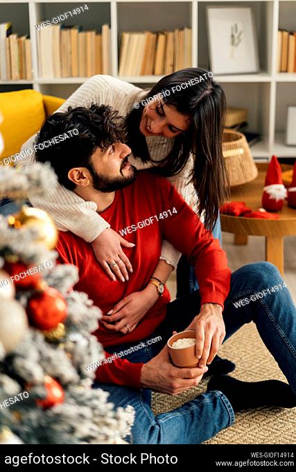 Smiling woman embracing boyfriend from behind at home