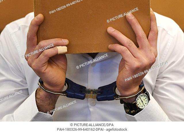 dpatop - 26 March 2018, Germany, Stade: The accused of attempted murder Mohamad Z. (L) holding a folder in front of his face in the court room. Z