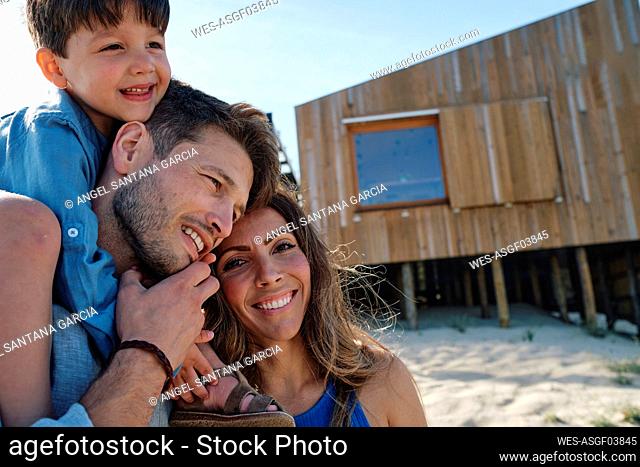 Happy family in front of beach house on sunny day