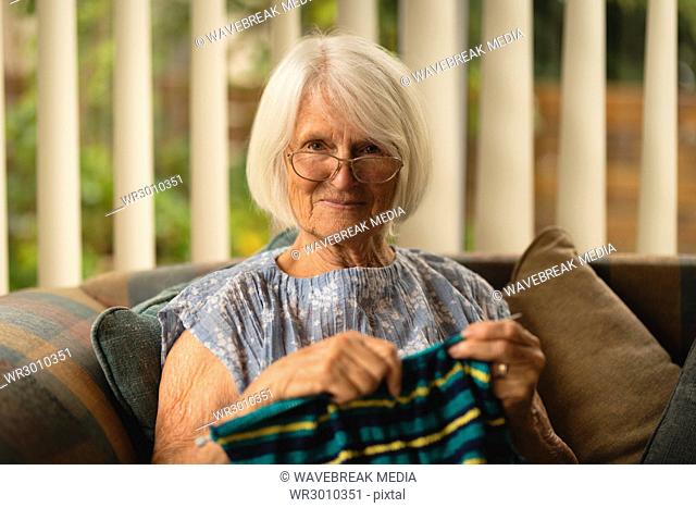 Senior woman knitting wool in living room