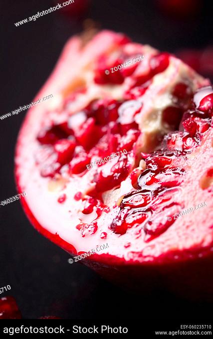Fresh juicy pomegranate with water droplets on a dark background, closeup, selective focus