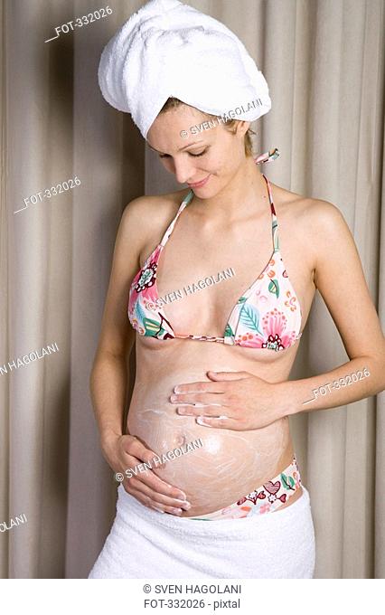 Pregnant woman rubbing moisturizer into her belly