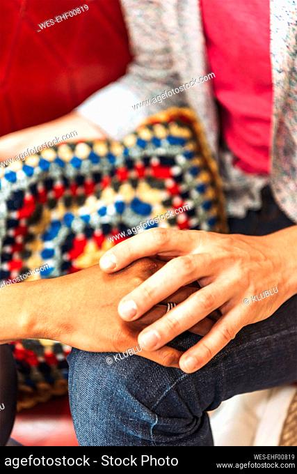 Close-up of couple holding hands in coffee shop