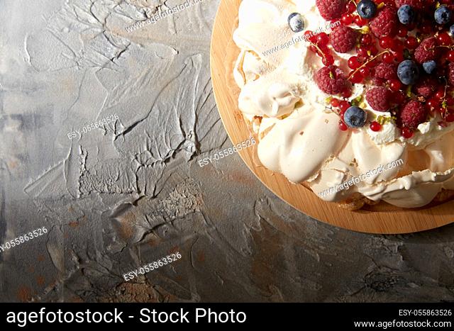 pavlova meringue cake with berries on wooden board