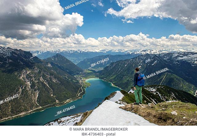 Hiker on hiking trail, crossing from the Seekarspitz to the Seebergspitz, view over the lake Achensee, Tyrol, Austria