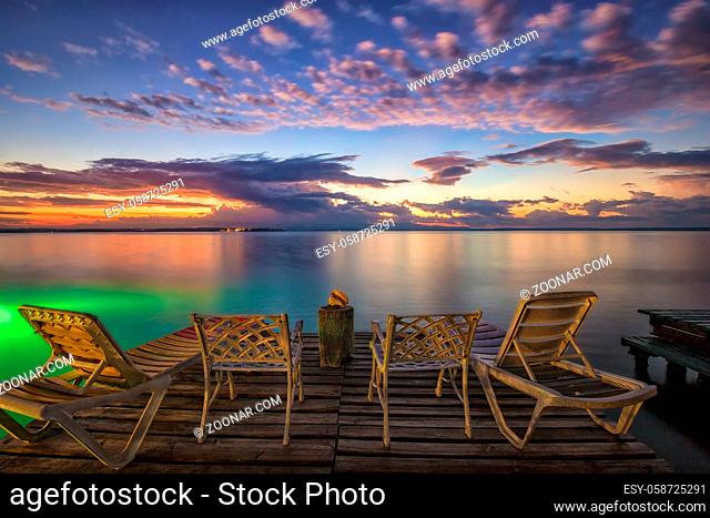 Empty deck chairs and chairs on a wooden pier waiting for sunrise on the sea beach