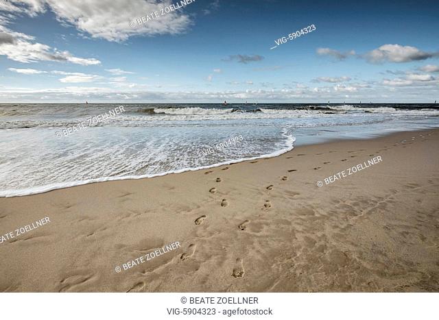 Spuren nackter Füße am Strand von Westerland/Sylt. Am Horizont bunte Windsurfsegel - es ist Anfang Oktober und gerade findet der Windsurfworldcup am...