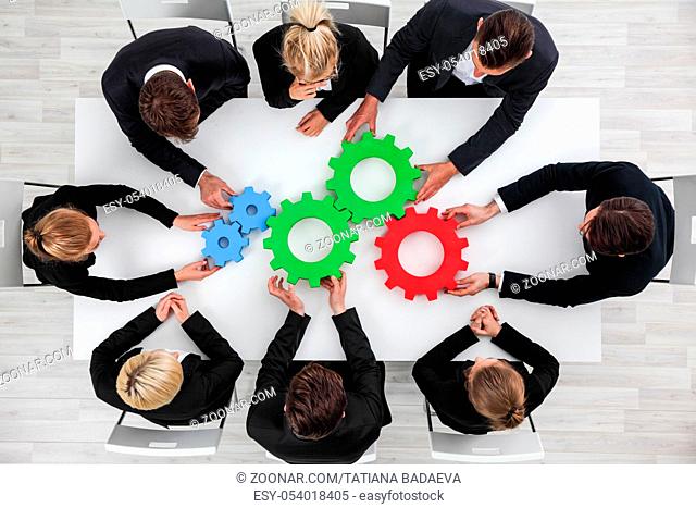 Business problem solution, mechanism of business, teamwork concept, business team sitting around white table with cogs