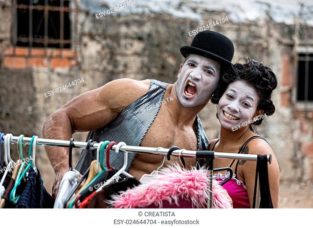 Laughing cirque clowns with makeup at clothing rack