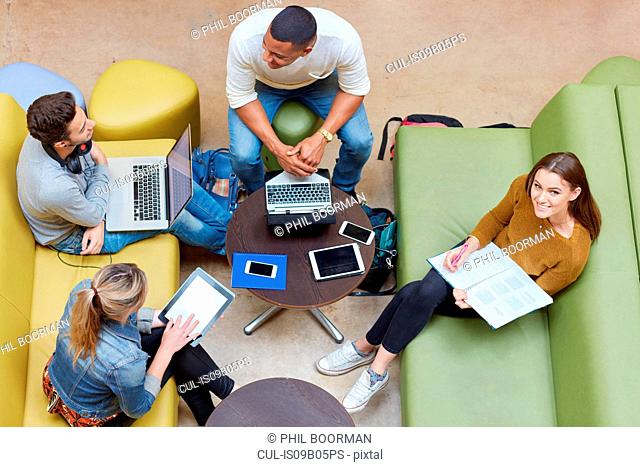 Overhead view of four male and female students brainstorming in higher education college study space