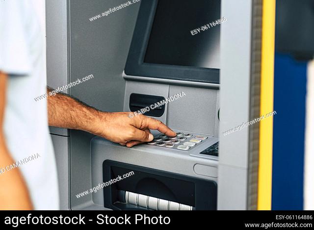 Close up of man hand withdrawing money at automatic atm machine typing secret ecurity code number. Concept of banking activity and business work