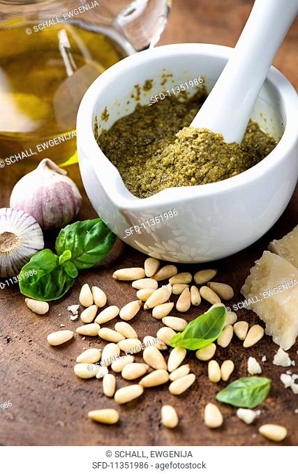 Pesto in mortar surrounded by ingredients