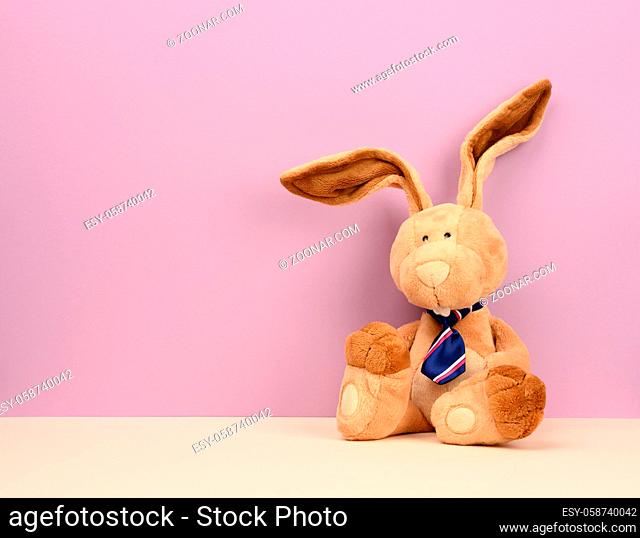 funny beige plush rabbit with big ears and funny face on a purple background, copy space