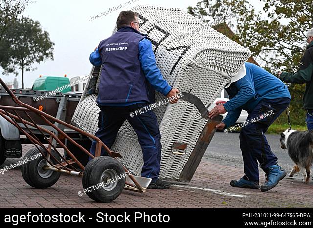 21 October 2023, Lower Saxony, Norden: Employees of Tourismus Norddeich help to load the beach chairs. North Sea lovers and bargain hunters have auctioned on...