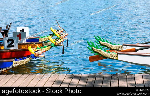 dragon boats moored at wooden pier or jetty at lake