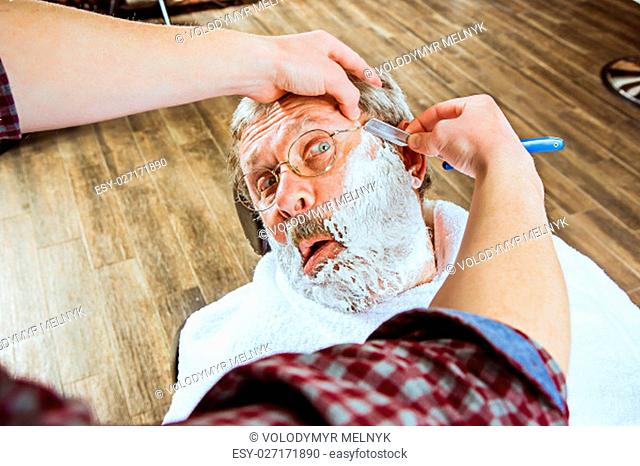 The emotional senior man visiting hairstylist in barber shop