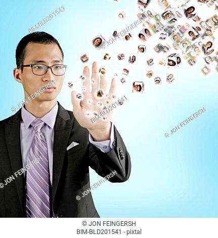 Asian businessman holding hand out to digital images