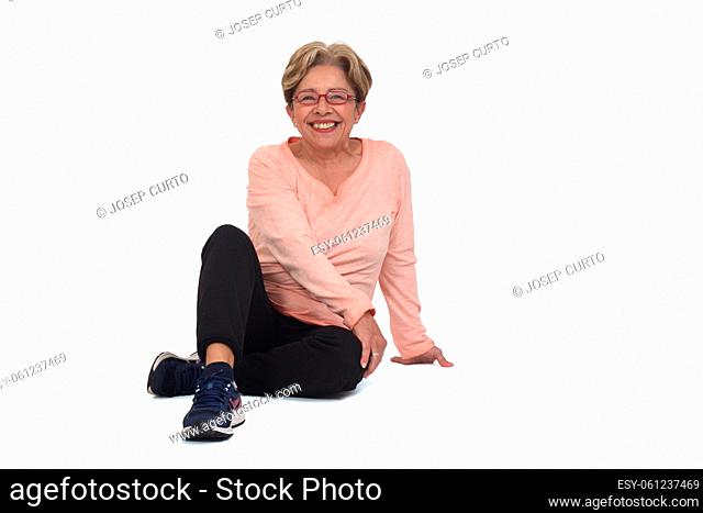 front view of a senior woman sitting on the floor looking at camera on white background