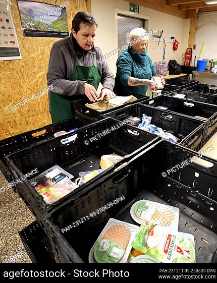 PRODUCTION - 07 December 2023, Mecklenburg-Western Pomerania, Rostock: At the food bank in Rostock, food is checked, sorted and reloaded into boxes to be...