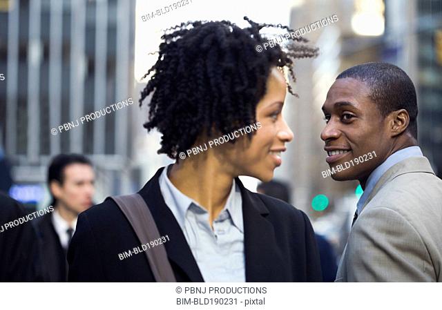 African American businesswoman smiling at businessman on street