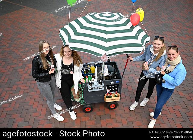 18 May 2023, Lower Saxony, Hesel: A group of young women stand by a handcart with a parasol and celebrate Father's Day 2023