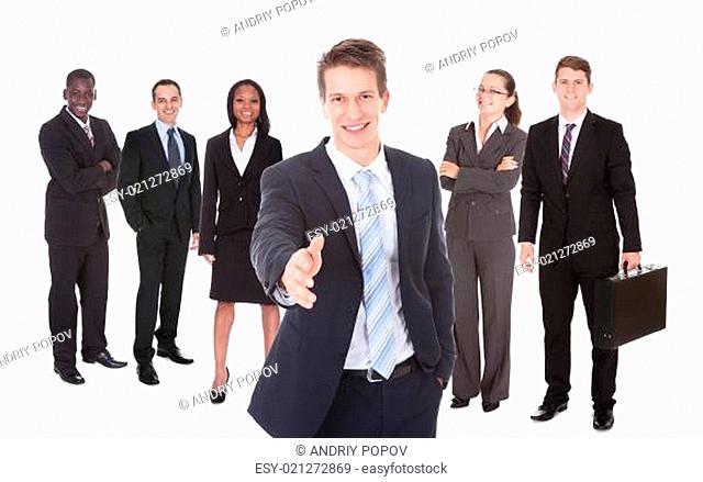 Businessman Offering Handshake With Team In Background