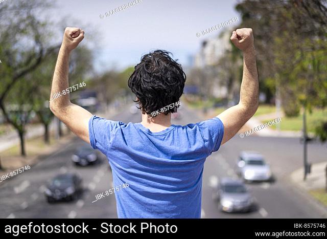 Successful man raising arms after running. Fitness male athlete with arms up celebrating success and goals after sport exercising