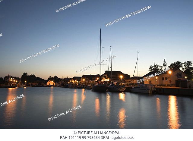 24 August 2019, Germany (German), Hiddensee: View to the harbour in Vitte shortly after sunset. Sailing ships are anchored at the quay wall
