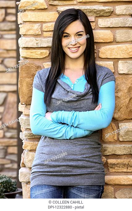 Portrait of a teenage girl standing against a stone wall; Oregon, United States of America