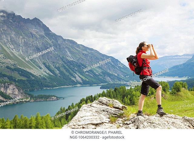 Hiker in the Engadine looking through binoculars, lake, nature, mountains, Switzerland, female, freedom, observing, searching, St