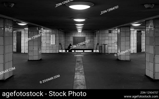 A woman is walking down the stairs in the subway station in black and white