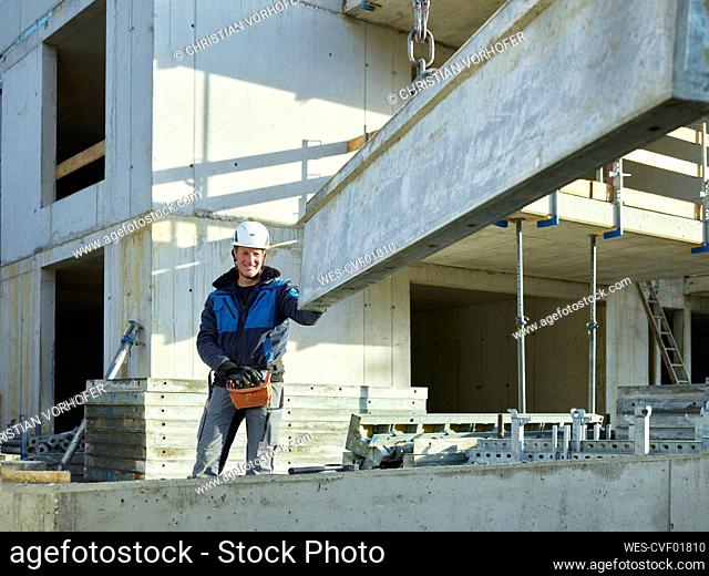 Smiling worker standing near construction material at site