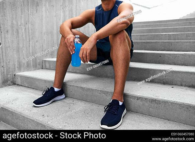 tired sportsman with bottle sitting on stairs