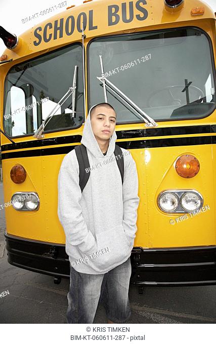 Young man with backpack next to school bus