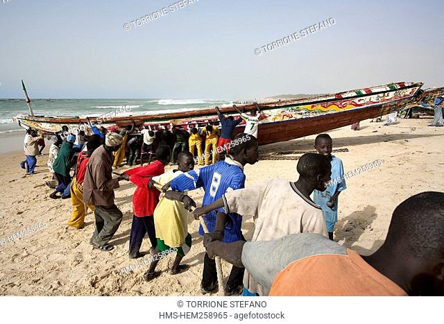 Senegal, Thies Region, Kayar, the beach and fishing harbour, fishermen pulling the dugout canoes onto the beach