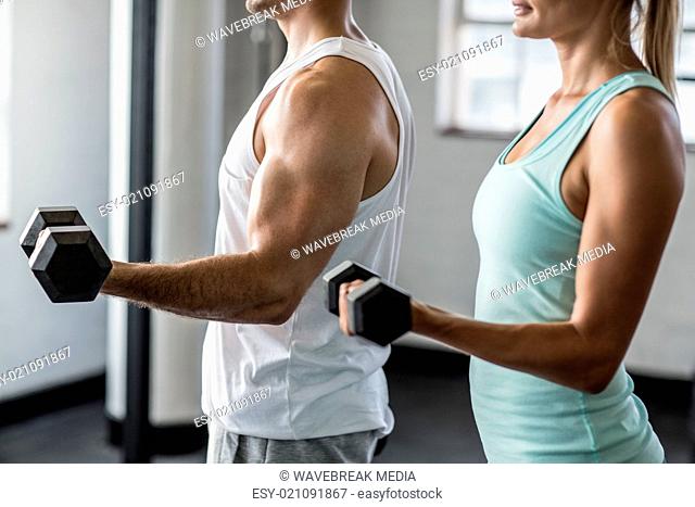 couple exercising with dumbbells in gym